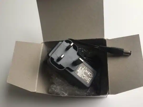 Laptop charger in open cardboard box.