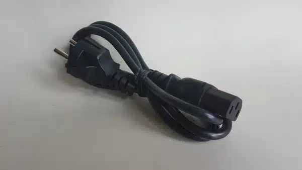 Black power cord with European plug folded on table.