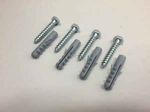 Silver screws and gray plastic anchors on table.