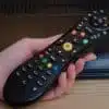 Hand holding a black television remote control.