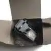 Black laptop charger inside cardboard box.