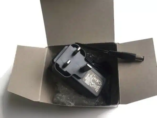 Black laptop charger inside cardboard box.
