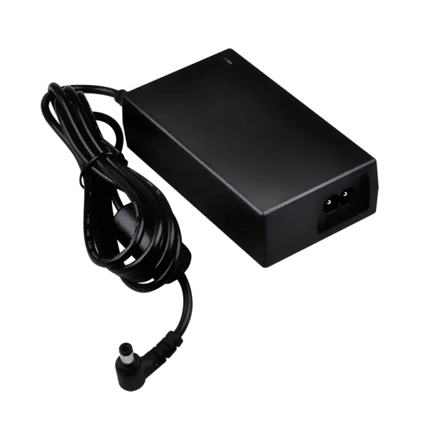 Black laptop power supply with cord on green background.