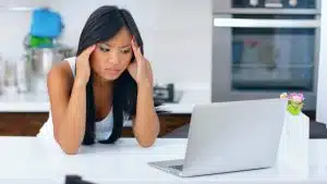 Woman looking stressed with laptop at home.