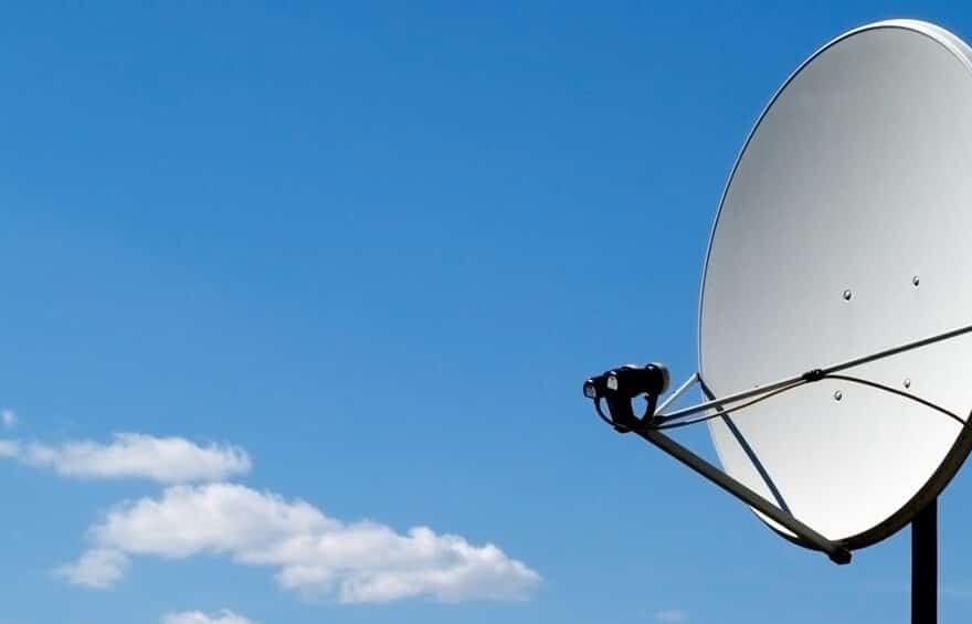 Satellite dish against blue sky with clouds.