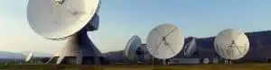 Satellite dishes at ground station, clear sky.